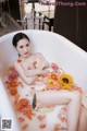 A woman laying in a bathtub filled with flowers.