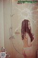 A woman standing in a bathroom next to a shower.