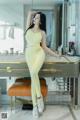 A woman in a yellow jumpsuit posing in front of a mirror.