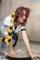 A woman in a sailor outfit crouching down with a hose.