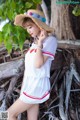 A woman in a white dress and a straw hat posing for a picture.