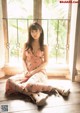 A woman sitting on the floor in front of a window.