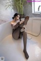 A woman sitting in a bathtub with her feet up in the water.