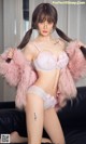 A woman in a pink lingerie sitting on a black couch.