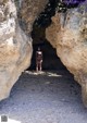 A woman in a purple bikini standing in a cave.
