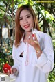 A woman in a white shirt holding a red heart.