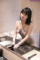 A woman in a gray lingerie is washing her hands in a sink.