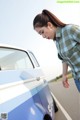 A woman leaning on the side of a blue and white car.