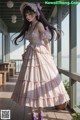 a woman in a pink dress standing on a porch