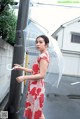 A woman in a red and white dress holding an umbrella.