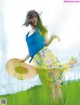 A woman in a blue tank top and yellow skirt is dancing in a field.