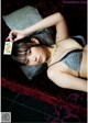 A woman laying on a couch holding a playing card.